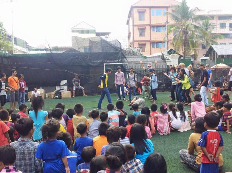 Slum outreach: Kids watch a skit of the story of David and Goliath (Goliath has just been slain and is lying on the ground.)